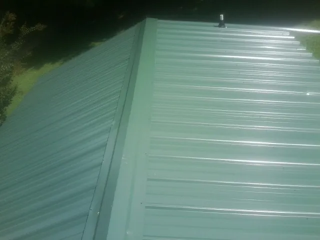 New green metal panels meeting at the ridge of a roof — Flat Roof Repair work by our crew in Smithfield
